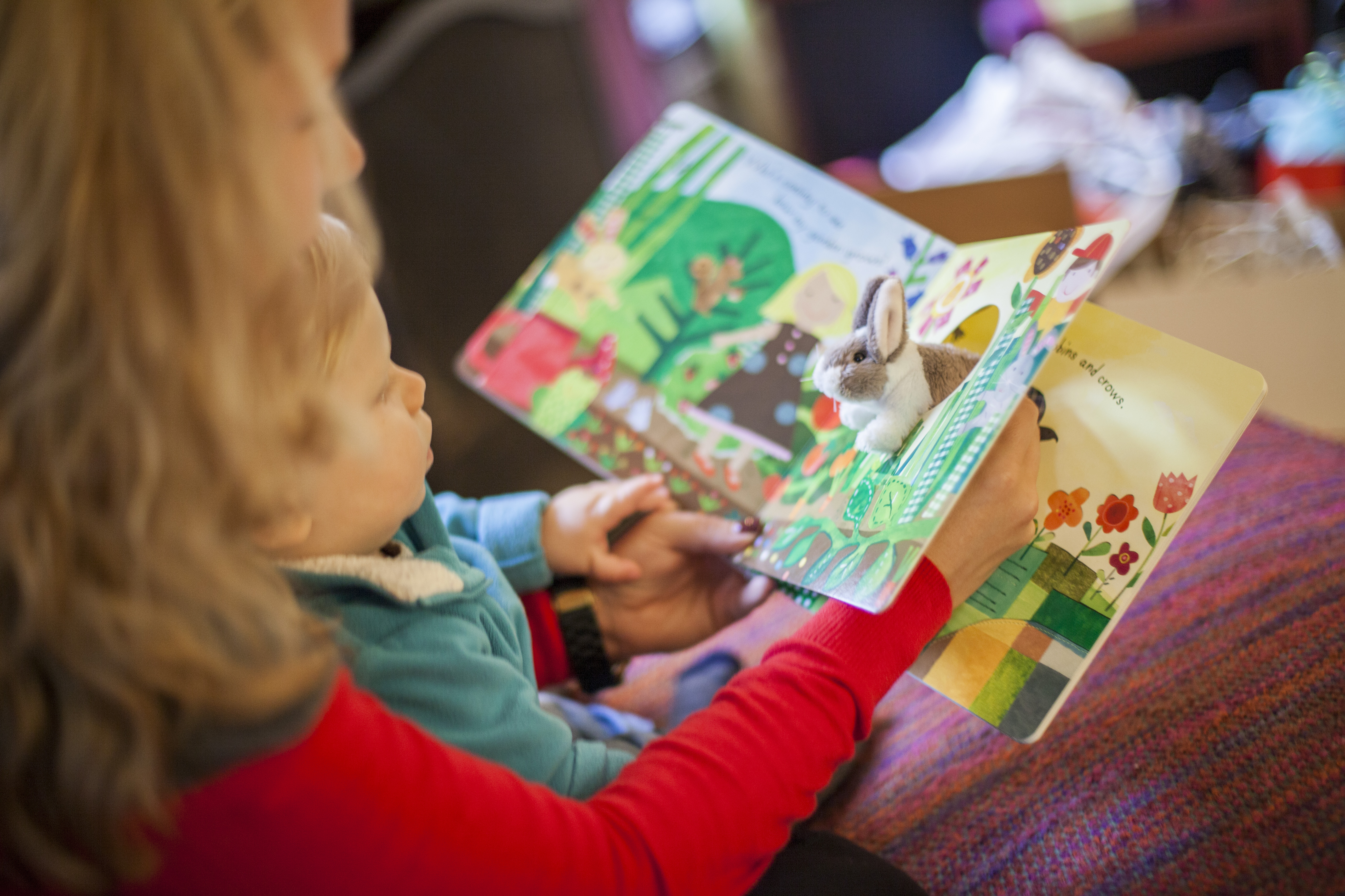 A parent reads a board book with her child.