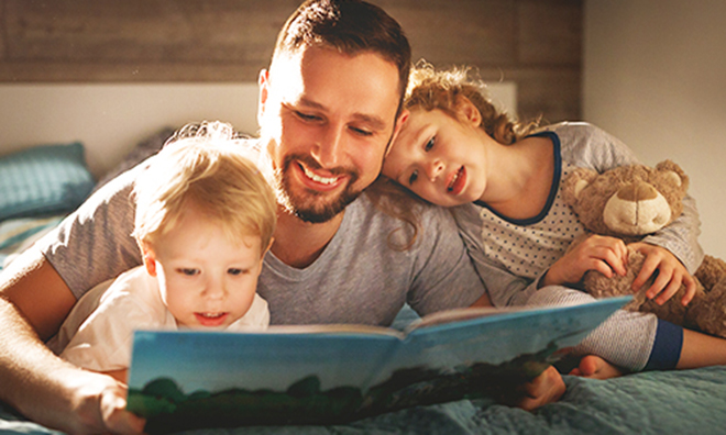 father reading a book to his two kids