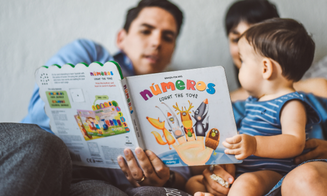 Parents reading a Spanish book to baby