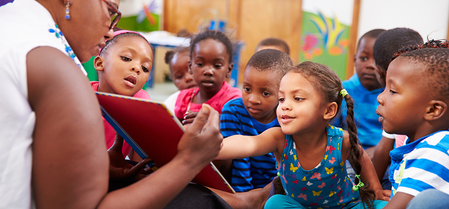 Teacher with book reading to kids