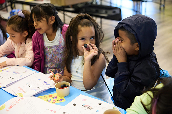 Children enjoying berries while completing activity sheets