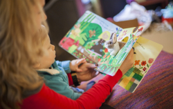 A parent reads a board book with her child.