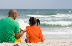Parent and child in front of beach with a book