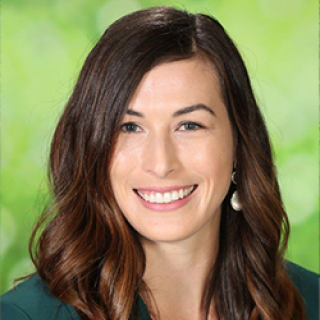 Erin Bailey smiles in front of a green background. She is the Director of Programs and Content at Reading Is Fundamental.