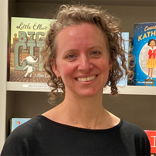 Kristin Shaffer, the Senior Director of Development at Reading Is Fundamental. In this picture, she stands in front of a bookshelf.