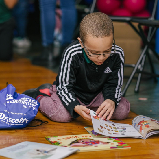 Young boy student reading a book on the floor