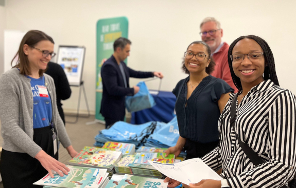 Employees smiling as they assemble literacy kits