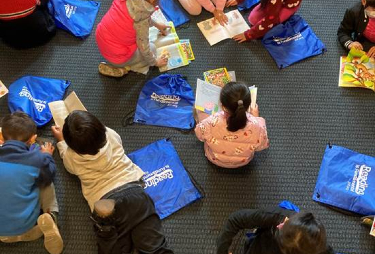 students kids reading on floor with bags Goldman Fund and RIF Read for Success