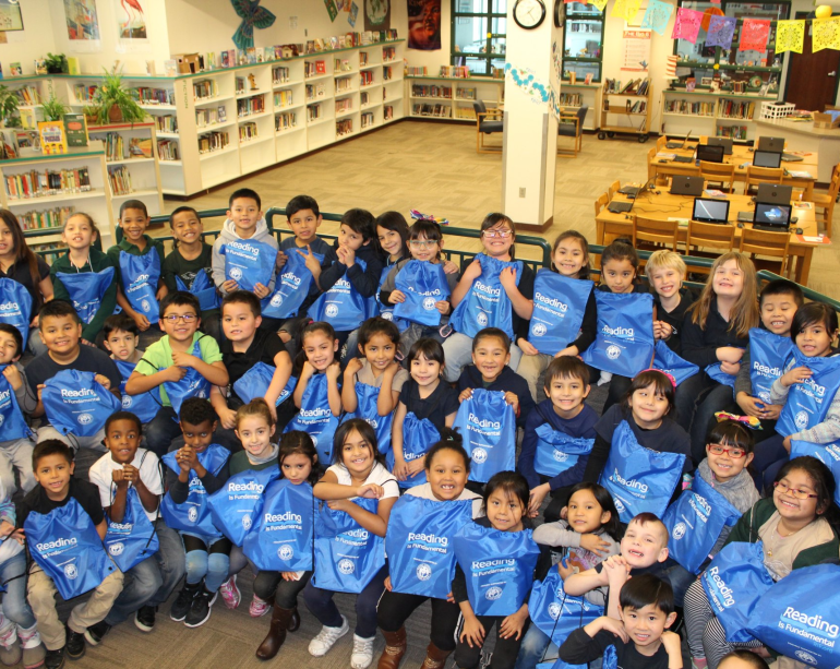 Group of students holding RIF bags reading literacy 