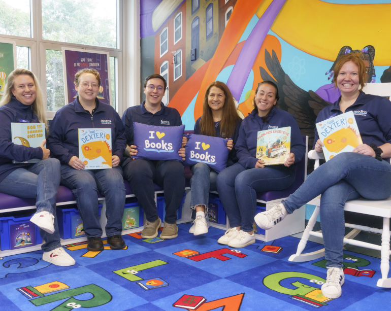 RIF staff sitting with books and throw pillows with I heart books